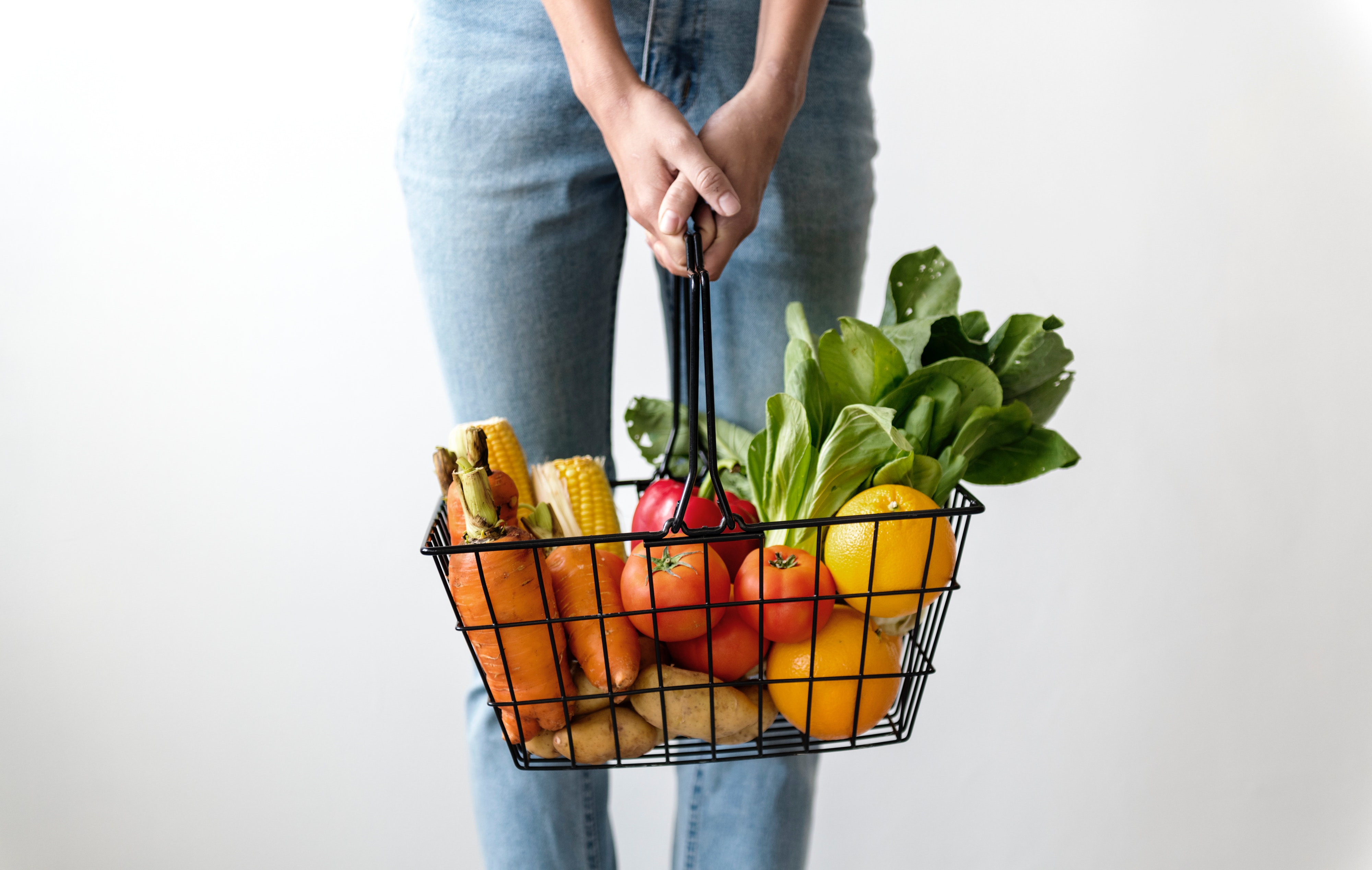 Mujer sosteniendo una canasta llena de frutas y verduras
